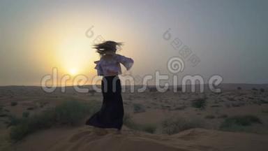 漂亮的女孩在沙漠里跳舞。 美丽的女人在日落时跳舞。 慢动作